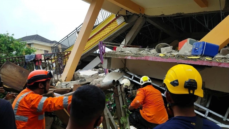 Miembros de los servicios de emergencias buscan supervivientes entre los escombros de un edificio en la ciudad de Mamuju, Indonesia.