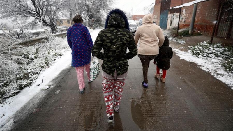 Varios residentes del asentamiento de la Cañada Real caminan bajo la nieve este jueves