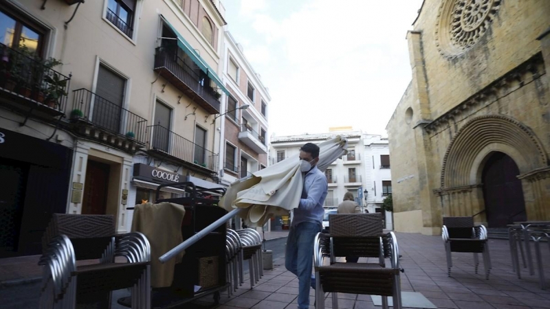 Un trabajador recoge el mobiliario de la terraza de un restaurante en el centro de Córdoba.