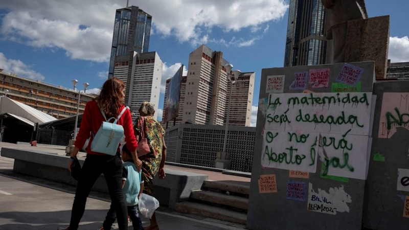 Varias personas caminan frente a un grafiti que dice 'La maternidad será deseada o no será aborto legal' en una pared, el 16 de enero de 2021, en Caracas (Venezuela). Una niña de 13 años que era abusada sexualmente por un vecino interrumpió, de manera vo