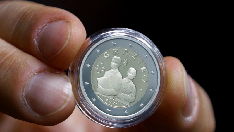 Un hombre muestra una moneda de dos euros que homenajea a los sanitarios.