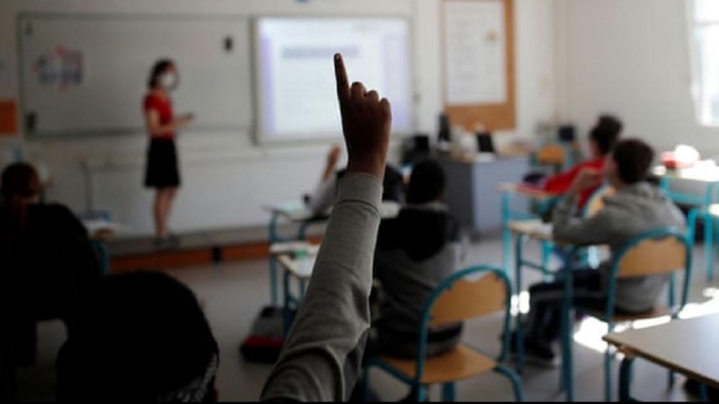 Un alumno levanta la mano en un aula.