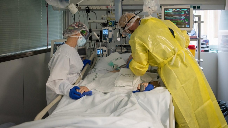 Dos sanitaris visitant un pacient de Covid a l'UCI de l'Hospital Clínic protegits amb EPI.