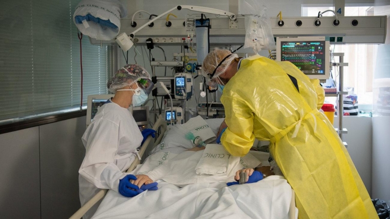 Dos sanitaris visitant un pacient de Covid a l'UCI de l'Hospital Clínic protegits amb EPI.