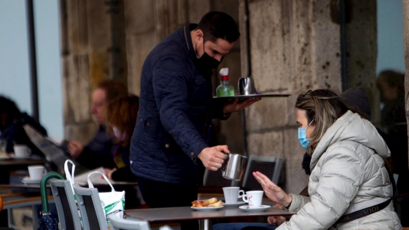 Un camarero sirve un café en la terraza de un bar en Vigo.