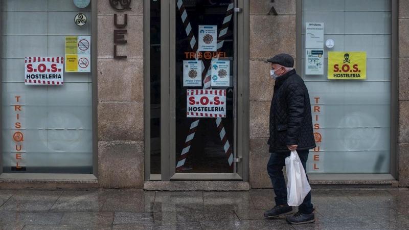 Un hombre camina junto a un bar cerrado en Xinzo de Limia, Ourense.