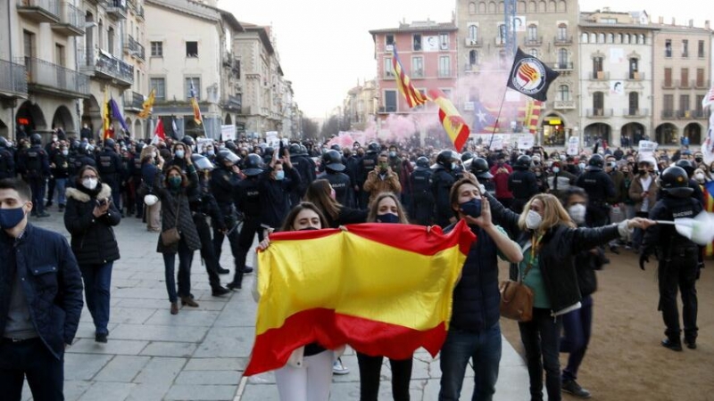 Seguidors de Vox amb una bandera espanyola davant de manifestants antifeixistes, separats per un cordó policial dels Mossos, a la plaça Major de Vic, en un acte de Vox, aquest dissabte passat.