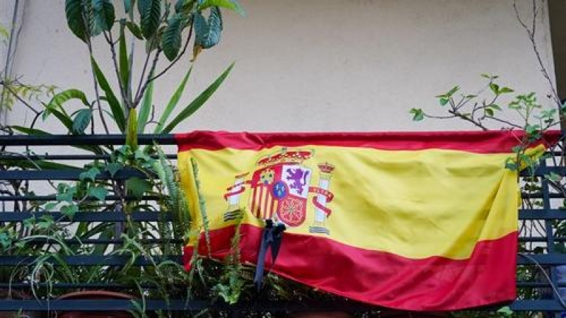 Banderas de España con crespones negros en un balcón.