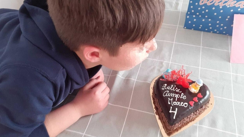 Marco, con 9 años, sopla la vela de la tarta con la celebra con su familia los 4 años como Marco.