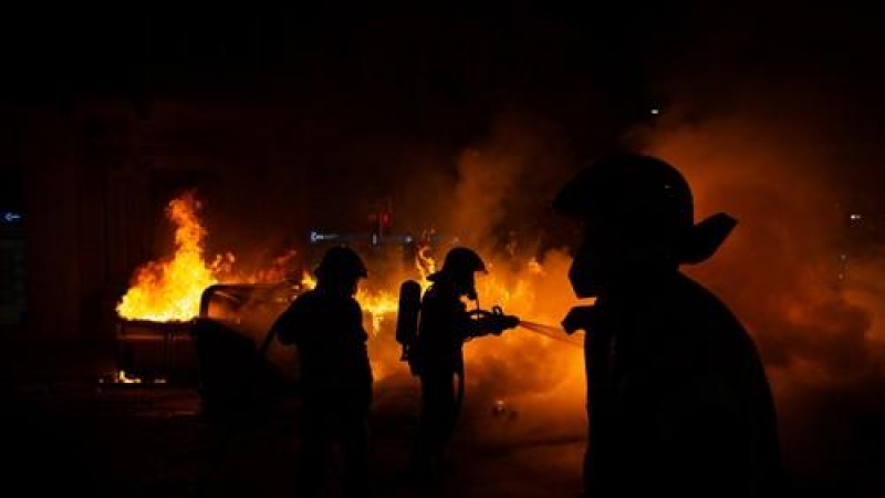 Els Bombers apaguen un foc generat en el transcurs dels aldarulls després de la manfestació per l'empresonament del raper Pablo Hasel a Barcelona.