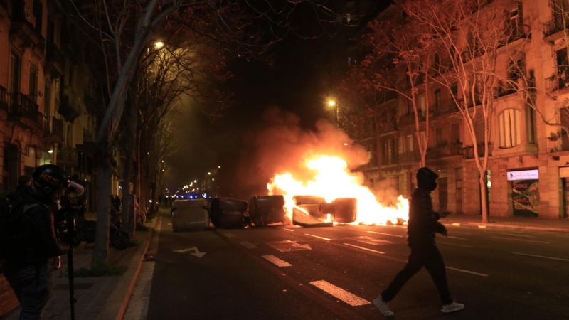 Un manifestant passa pel davant d'una barricada de contenidors cremant a Barcelona el 18 de febrer del 2021.