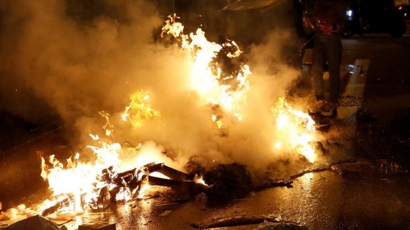 Restos de contenedores ardiendo en el centro de Barcelona este sábado, durante las protestas por el encarcelamiento del rapero Pablo Hasél.