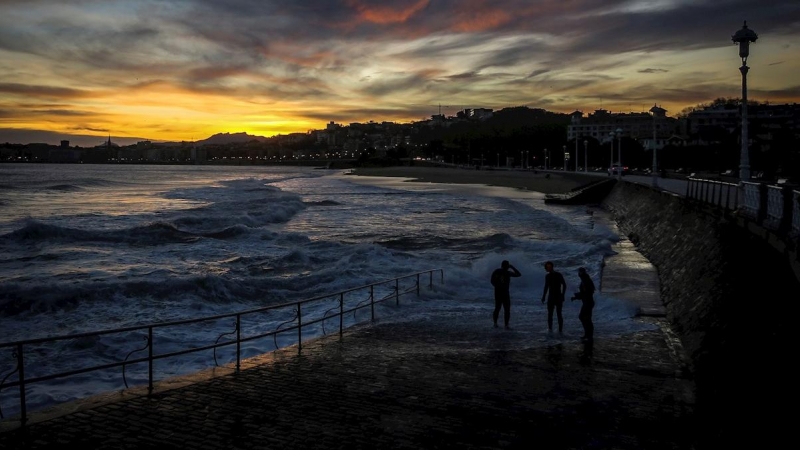 Tres hombres observan la playa de Ondarreta, en San Sebastián, al amanecer. - EFE