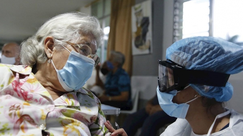 Una sanitaria conversa con una mujer antes de aplicarle la vacuna contra la covid en Medellín, Colombia.
