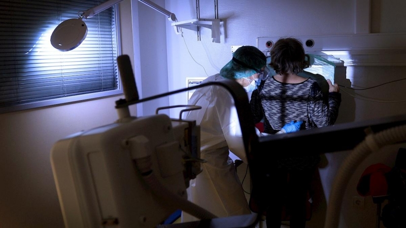 Una técnica de rayos X realiza una placa a una mujer con síntomas de covid.