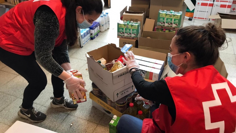 Dues voluntàries de Creu Roja preparen lots d'aliments.