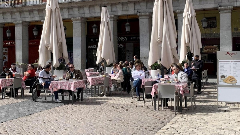 Varios turistas en su mayoría franceses disfrutan del sol en la Plaza Mayor de Madrid.