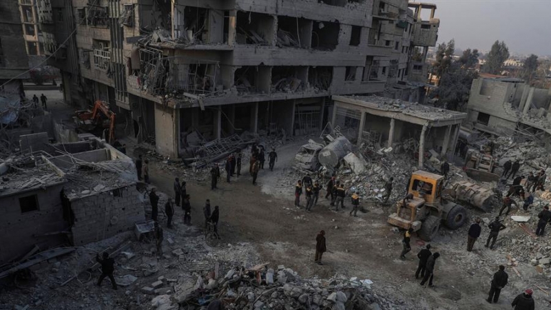 Foto de archivo (09/01/2018) de civiles y voluntarios de la Defensa Civil Siria mientras buscan sobrevivientes después de que varios ataques aéreos destruyeran edificios en la ciudad de Hamoria, al-Ghouta (Siria).