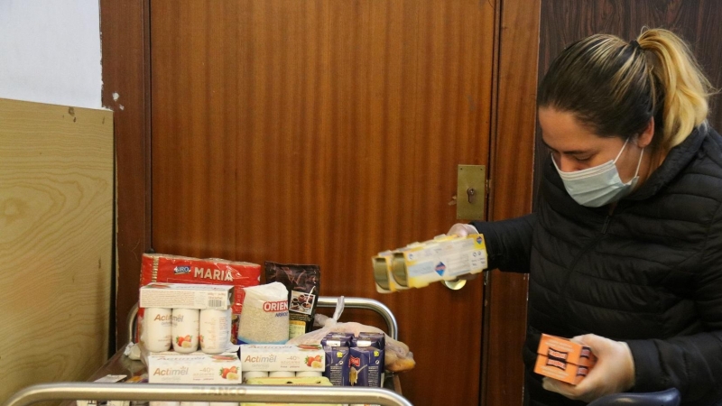 Una dona omple un carro de menjar a un punt de distr​ibució d'aliments de Cáritas a Les Corts.