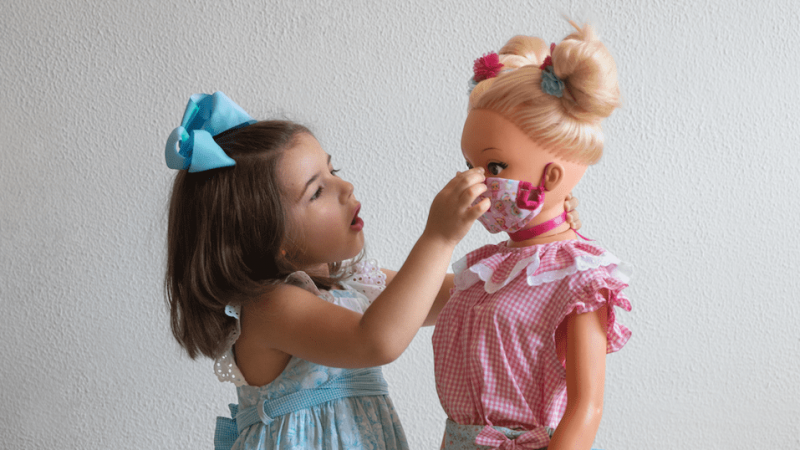 Una niña pone una mascarilla a su muñeca. - Cristina García Rodero