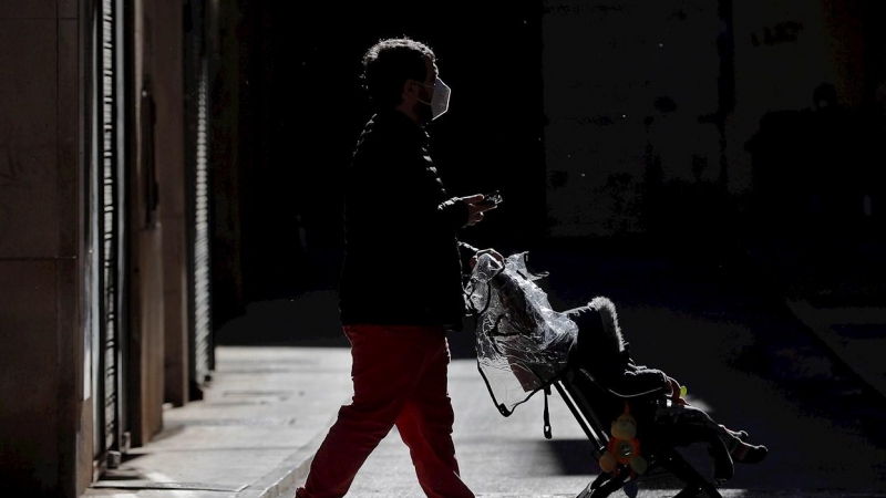 Un hombre pasea con un carrito de bebé por la ciudad de València.