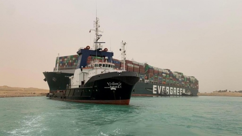 Un barco vigila el buque portacontenedores que fue golpeado por un fuerte viento y encalló en el Canal de Suez, Egipto.