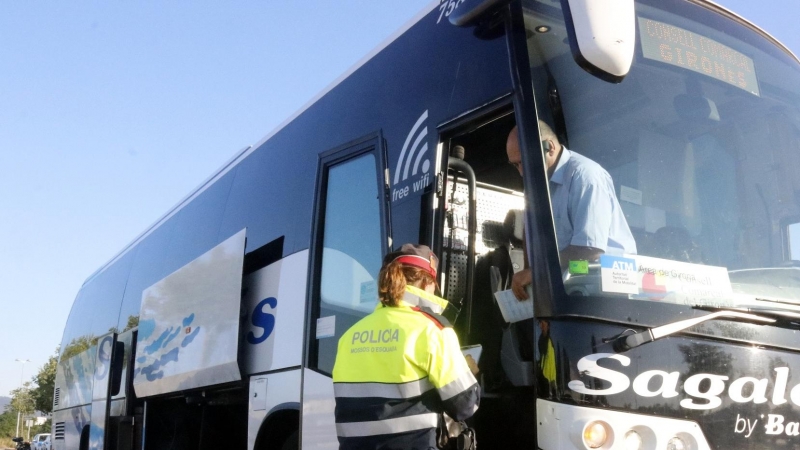 Un Mosso controla la documentació d'un bus.