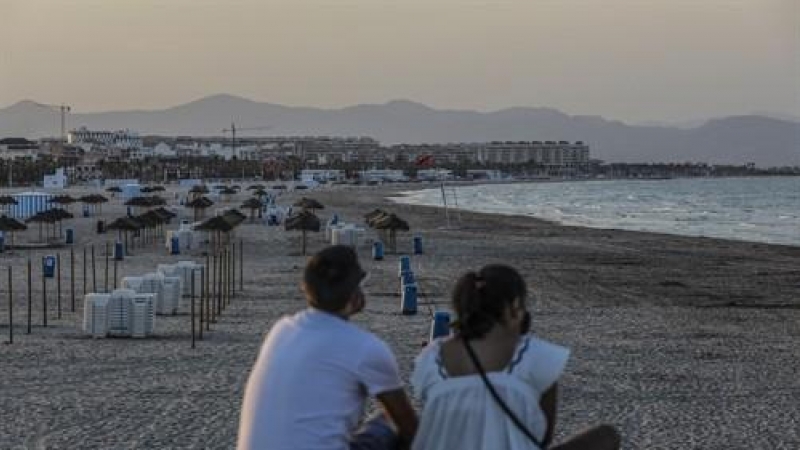 Dos jóvenes sentados contemplan la playa de la Malvarrosa durante la noche de San Juan en Valencia, Comunidad Valenciana (España), a 23 de junio de 2020.