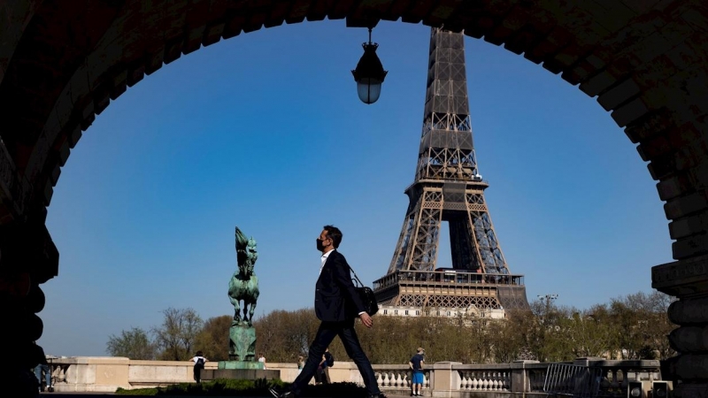 31/03/2021. Un peatón con mascarilla anda por el puente Bir Hakeim cerca de la Torre Eiffel poco antes de que Macron anunciara las nuevas restricciones, este miércoles en París. - EFE