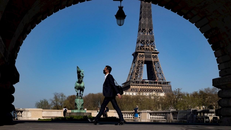 31/03/2021. Un peatón con mascarilla anda por el puente Bir Hakeim cerca de la Torre Eiffel poco antes de que Macron anunciara las nuevas restricciones, este miércoles en París. - EFE