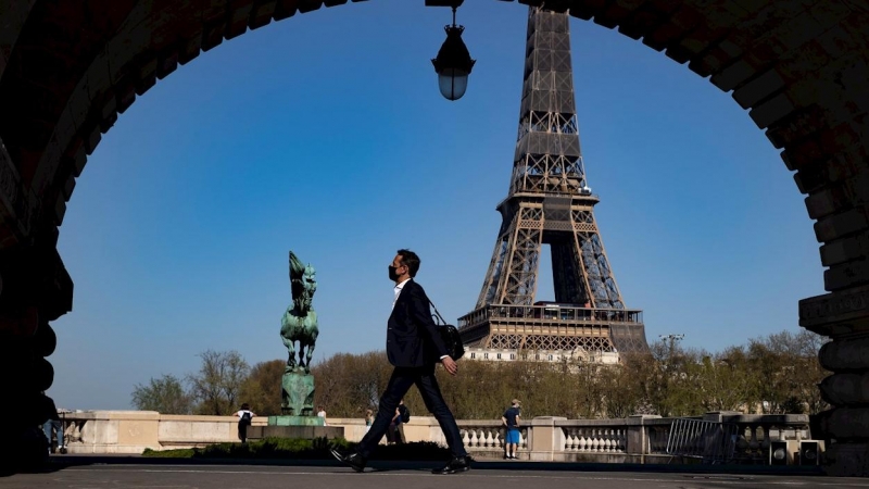 31/03/2021. Un peatón con mascarilla anda por el puente Bir Hakeim cerca de la Torre Eiffel poco antes de que Macron anunciara las nuevas restricciones, este miércoles en París. - EFE