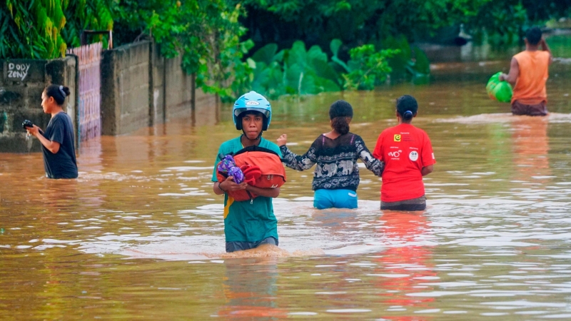04/04/2021. Un hombre con casco lleva consigo sus pertenencias en un área afectada por las fuertes inundaciones en Indonesia y Timor Oriental. - Reuters