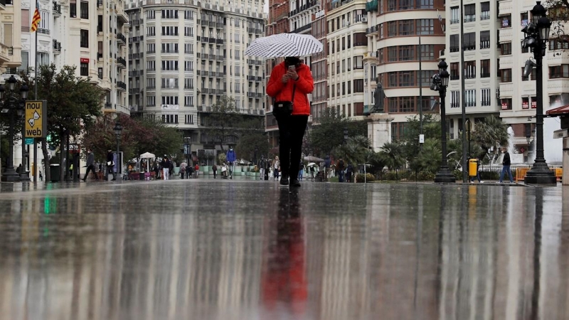 09/04/2021. Una persona se protege de la lluvia con un paraguas este viernes, en València. - EFE