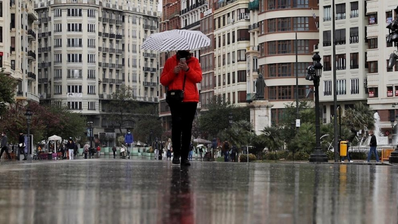 09/04/2021. Una persona se protege de la lluvia con un paraguas este viernes, en València. - EFE