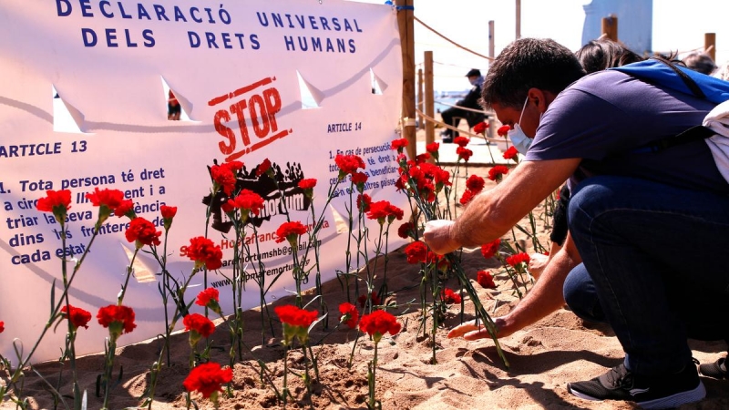 Un home plantant un clavell a la sorra de la platja. Imatge del 18 d'abril del 2021.