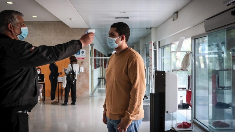 Personal de seguridad toma la temporada a un estudiante en la entrada de la facultad de Derecho de la Universidad de Lisboa.