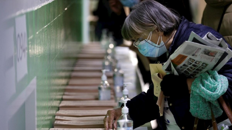 04/05/2021.- Una mujer escoge una papeleta para ejercer su derecho al voto en el colegio La Inmacualada-Marillac en Madrid durante la jornada electoral.