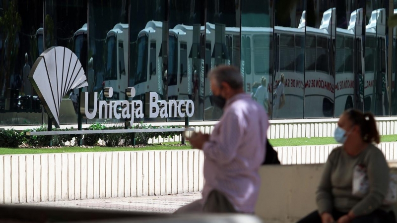 Dos personas en las inmediaciones de la sede de Unicaja Banco en Málaga. E.P./Álex Zea