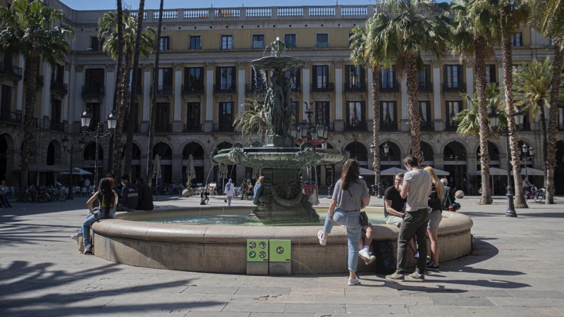 Uns joves descansen i parlen a la font de la plaça Reial