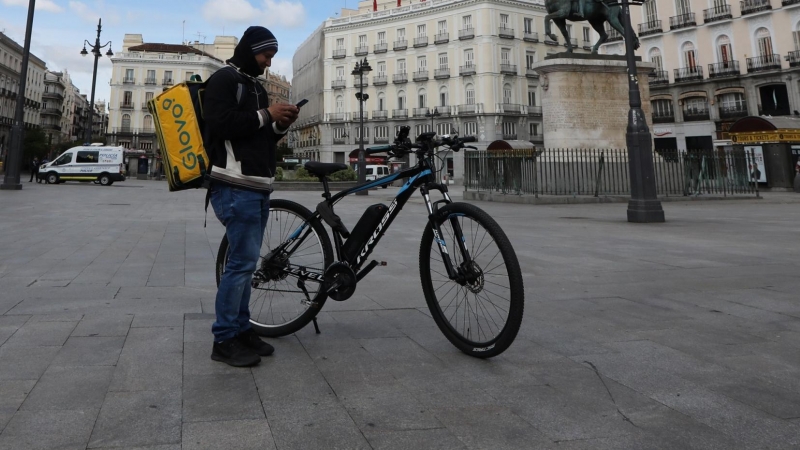 Un repartidor de la empresa Glovo mira su teléfono en la Puerta del Sol.