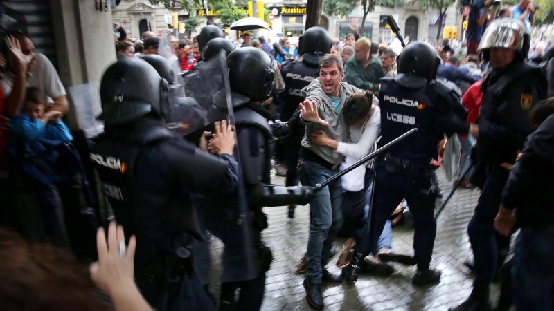 Un home intenta protegir una dona dels cops de porra d'agents antidisturbis de la policia espanyola l'1 d'octubre d'aquest 2017.