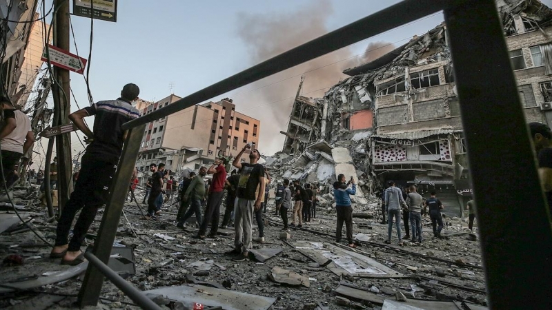 Un grupo de palestinos inspeccionan los restos de una torre destruida por un bombardeo israelí.