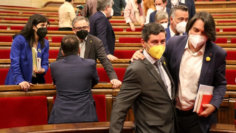 Pla conjunt dels negociadors d'ERC i Joan Candell i Francesc de Dalmases (JxCat) passant pel costat a l'hemicicle del Parlament el 13 d'abril del 2021.