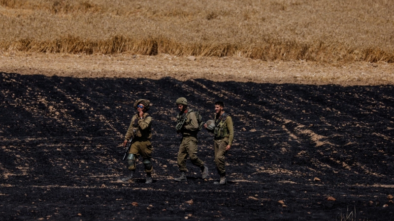 Soldados de Israel caminan en un campo cerca de la frontera entre Israel y la Franja de Gaza