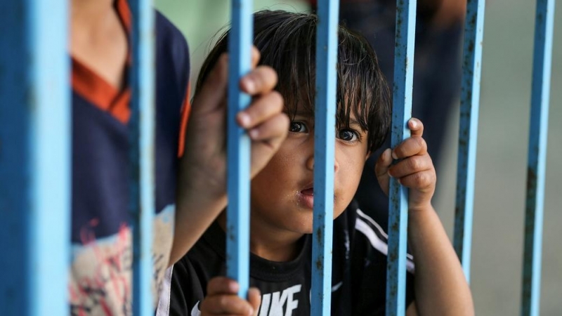 Un niño palestino, que huyó de su casa con su familia debido a los ataques aéreos y de artillería israelíes, mira a través de una barandilla en una escuela dirigida por las Naciones Unidas donde se refugian, en Gaza.