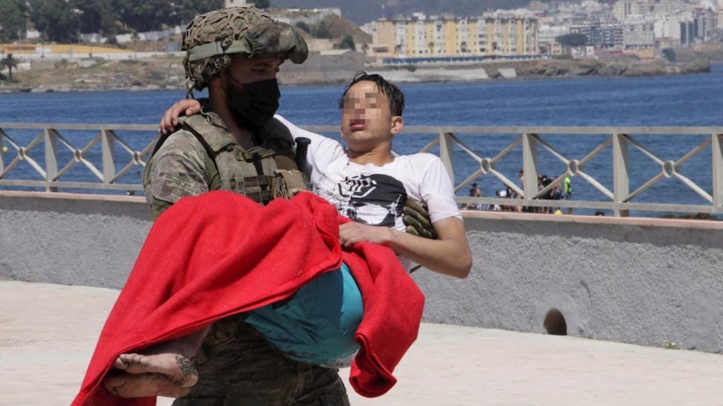 Un soldado traslada a un inmigrante en la playa fronteriza de El Tarajal de Ceuta.