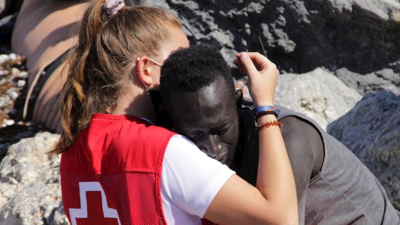 Una trabajadora de la Cruz Roja y un migrante que ha logrado cruzar uno de los espigones fronterizos de Ceuta.