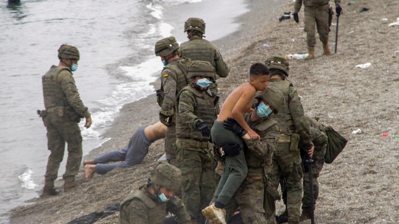 Miembros del Ejército de Tierra ayudan a un grupo de inmigrantes que han logrado cruzar uno de los espigones fronterizos de Ceuta.
