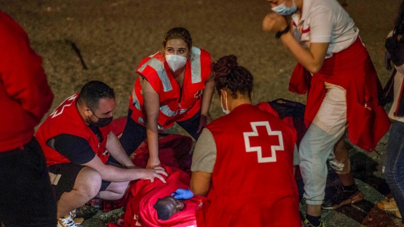 Efectivos de Cruz Roja atienden a un migrante con signos de hipotermia tras intentar cruzar a España por el agua en la playa de El Tarajal este miércoles 19 de mayo de 2021.