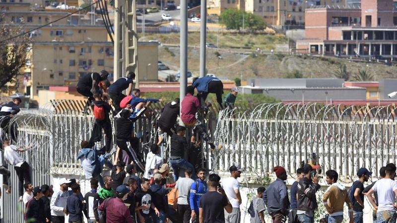 Jóvenes marroquíes encaramados a la valla en la ciudad de Fnideq en un intento por pasar a suelo español este martes 18 de mayo de 2021.